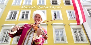 A Mozart performer plays the violin in front of Mozart's birthplace | © Tourismus Salzburg GmbH / B. Reinhart