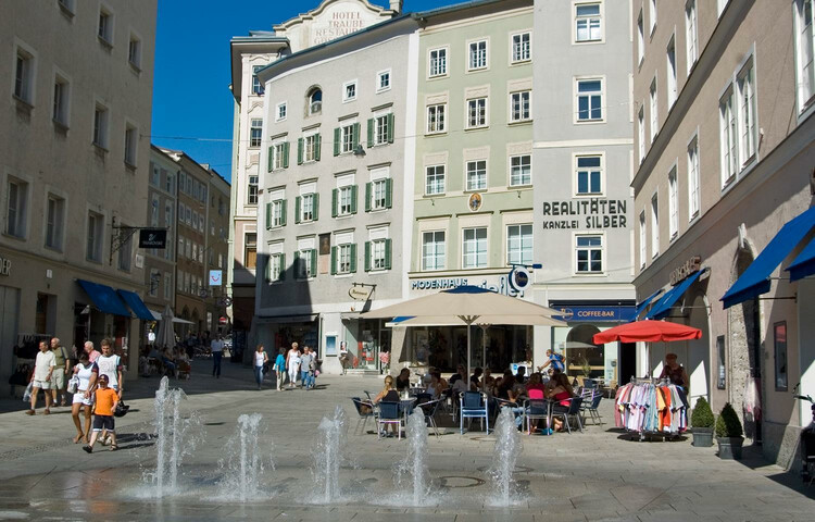 Linzergasse in Salzburg Austria with shops and people sitting at an outdoor cafe